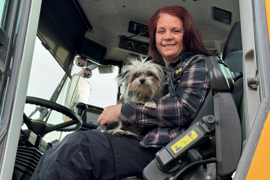 Medarbetare Maria Öhlen sitter i sin traktor med en hund.